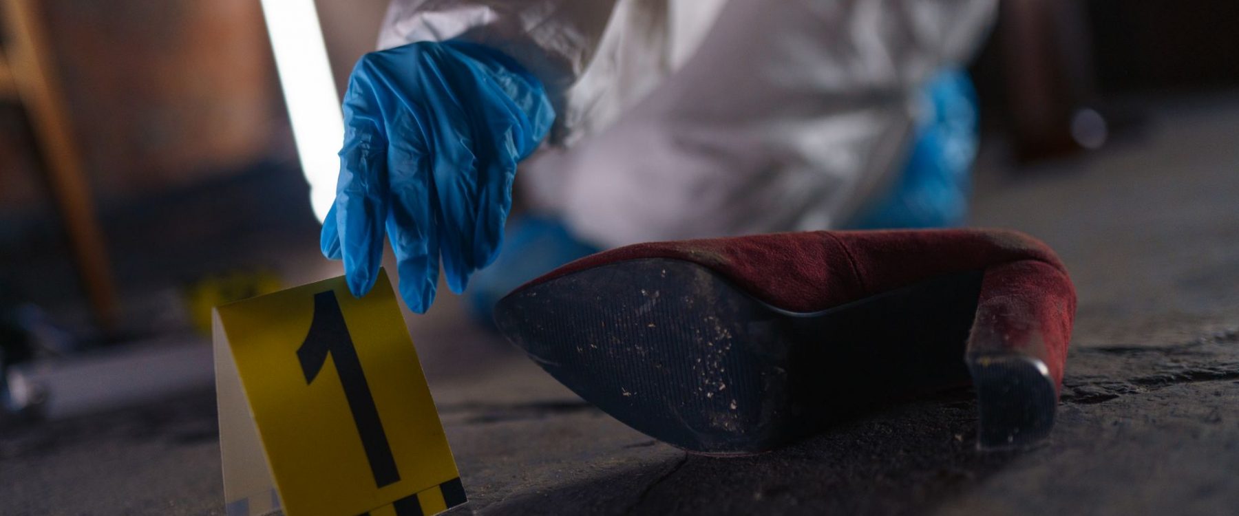 hand putting evidence number on pavement on crime scene