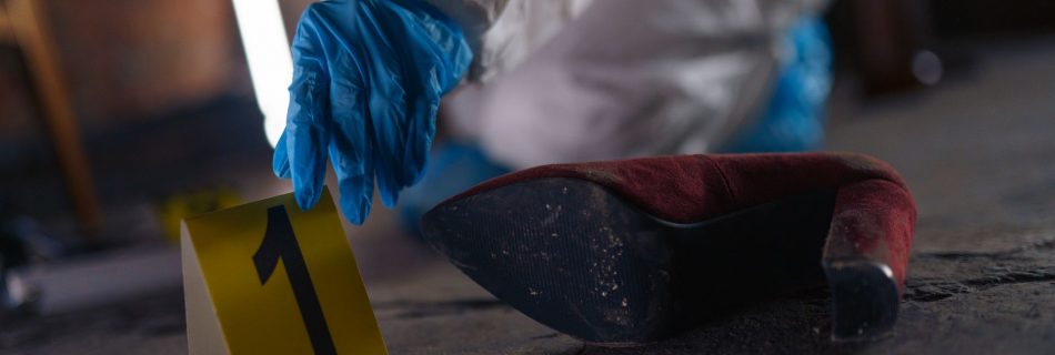 hand putting evidence number on pavement on crime scene