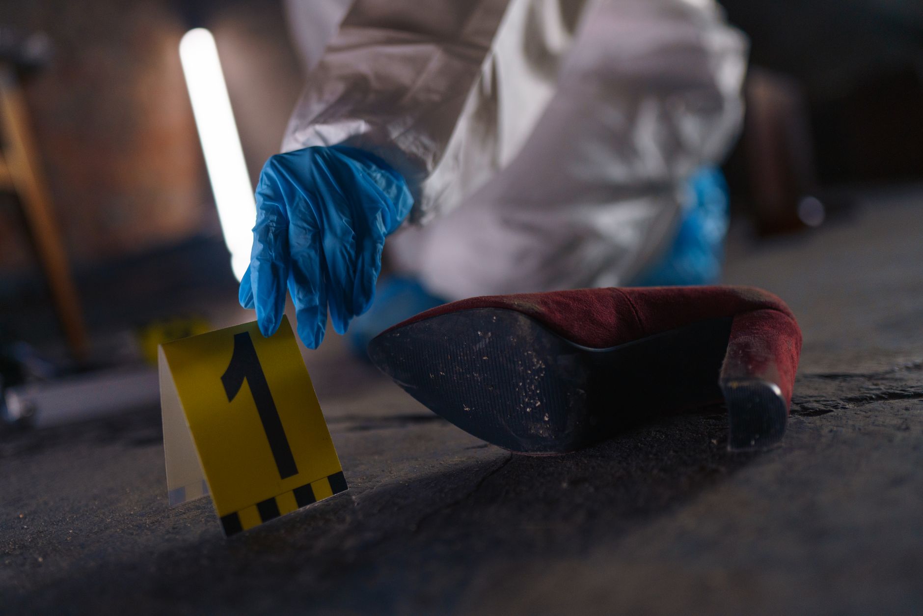hand putting evidence number on pavement on crime scene