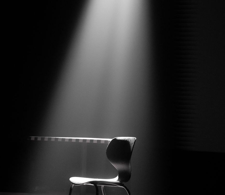 minimalistic spotlight on black chair in dark room