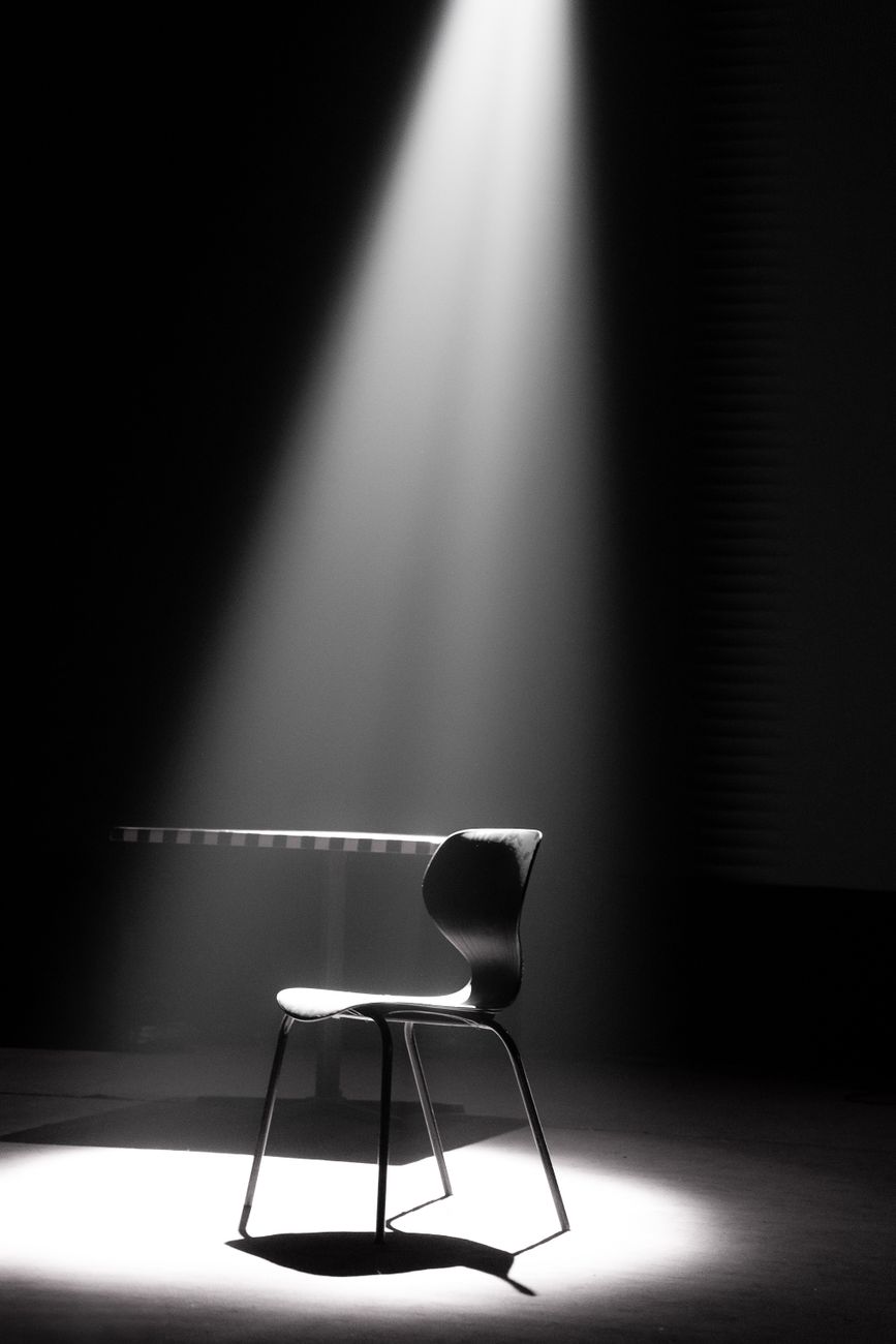 minimalistic spotlight on black chair in dark room